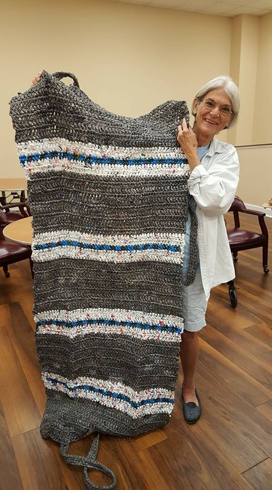 Sara Rice Chapman holds up a bedroll made from woven plastic bags.