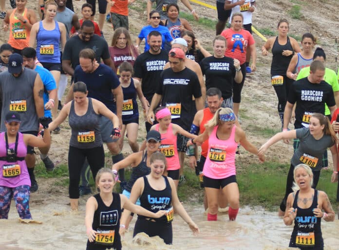 Runners plunge into a mud pit at Mud Endeavor 10 on May 19, 2018.