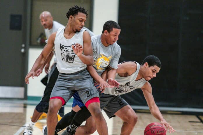 Freshman Chris Brown attempts to guard PHSC Alumni player Travis Fletcher as  Antonio Tucker attempts to take control of the ball.