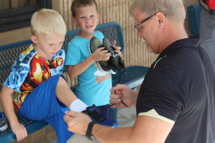 Principal Gaustad helps one of his students try on a pair of donated shoes before the start of school .