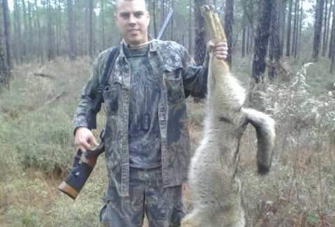 DC Sims of Brooksville holding an invasive coyote successfully harvested with his own homemade calls.