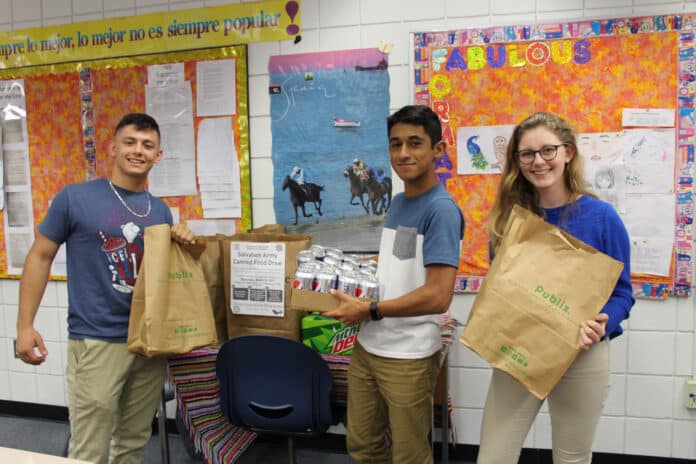From left to right: Jason Bienstock, President of Interact Club, Rayaan Kader, underclassmen Interact Club President and Victoria Harding, Club Secretary hold some of the bags and items collected for the food drive.