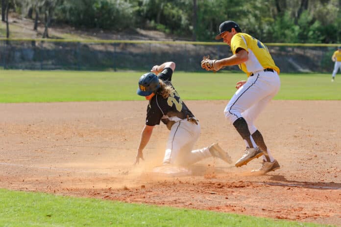 Alumni player Riley Choate slides into third base as freshman Connor Berry tags him out. 