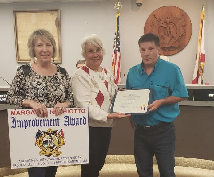 On Monday, April 1, 2019 the City of Brooksville Beautification Board presented two Improvement Awards named after Margaret Rogers Ghiotto.  The Margaret R. Ghiotto Commercial Improvements Award was presented by Brooksville Beautification Board Chair Ronette Snyder and Vice Chair Kathy Middleton to John Loetscher of Country Depot, 36 N. Broad St. at the Brooksville City Council meeting.  Absent from photo is James White, III, who received the Margaret R. Ghiotto Residential Improvement Award.  Residents of