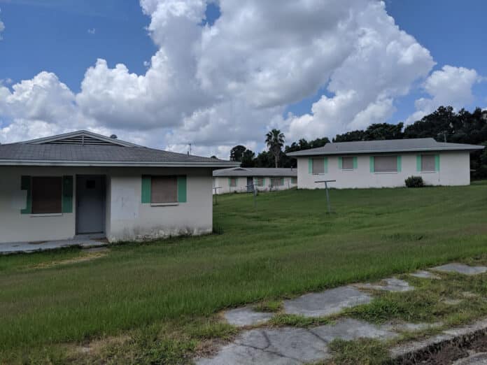 Homes in Hillside Estates remain boarded up, but lawns seem well cared for.