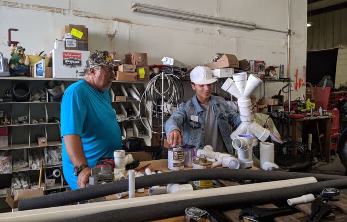 Gioones Lamos assembles PVC piping with the assistance of instructor Dennis Harman.