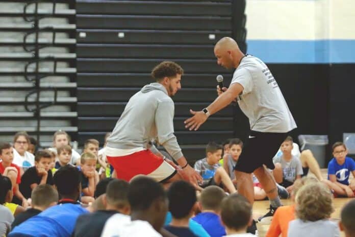 Head varsity basketball coach David Pisarcik with recent graduate Robert Gomez.  Gomez is demonstrating dribbling techniques during the basketball camp held at Nature Coast Tech.