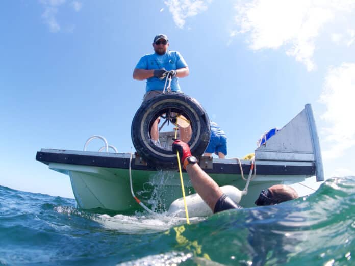 Hoisting the tire into the boat using a rope line.  Photo courtesy of Brian Kelly.