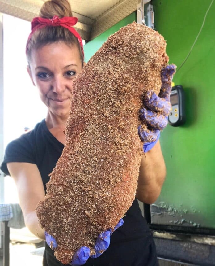 Laurie-Ann Wilkens holds a large cut of meat on its way to the smoker