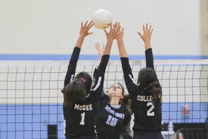 NCT Madison Clark sets the ball over the net as Hornets Danielle Mcgee (1) and Grace Colleran (2) attempt to block.