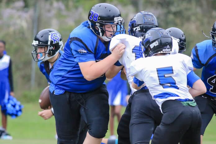 Lion 6’ 2” Dawson Kilcrease pushes to block First Christian’s defense line players in order for Jordon Kilcrease to gain yardage towards a first down