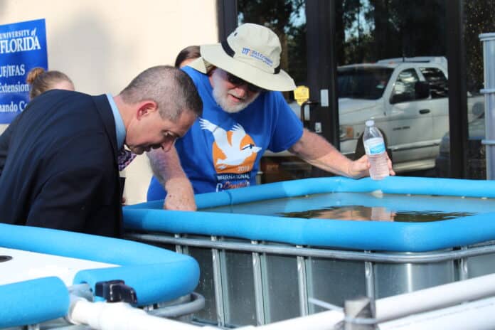 UF/IFAS Extension volunteer Sarge Dendy shows County Commissioner John Mitten the tank where they are growing eel grass and mosquito fish.
