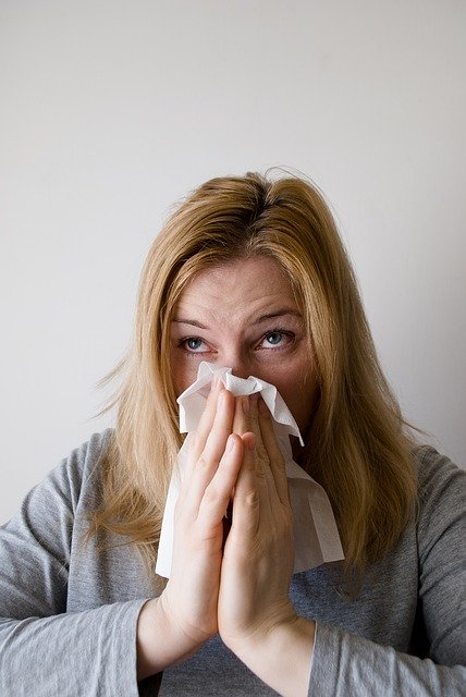 File photo of a woman in robe holding tissue to nose