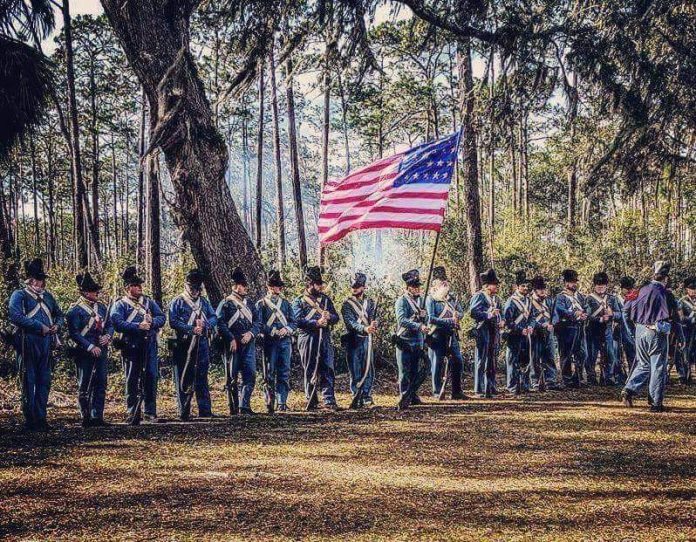 The group prior to battle surrounding the late Frank Laumier, historian and author, who was instrumental in starting the reenactment years ago.