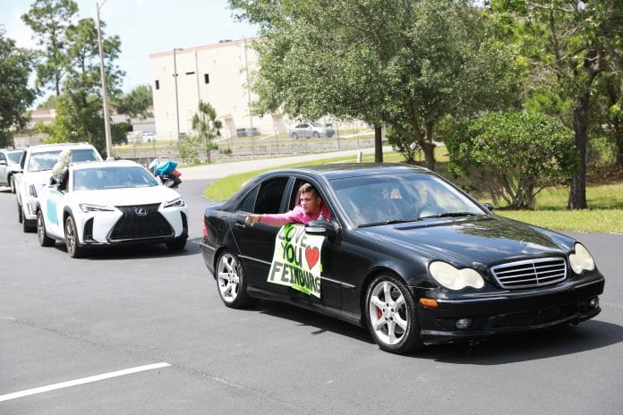 Students honor David Feinberg with special messages on handmade signs as they drive by his window at the Hospice facility.  Photo courtesy of Trevor Barlow, Monocle Designs Solutions