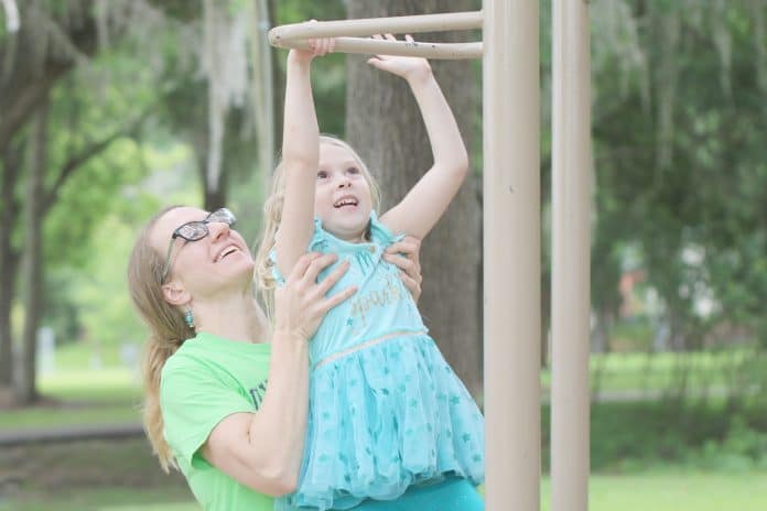 Emily Ollivier helps her daughter, Scarlett Rose reach for the bar at Tom Varn Park on May 10th.