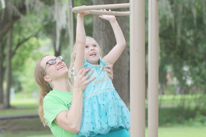  Emily Ollivier helps her daughter, Scarlett Rose reach for the bar at Tom Varn Park on May 10th.