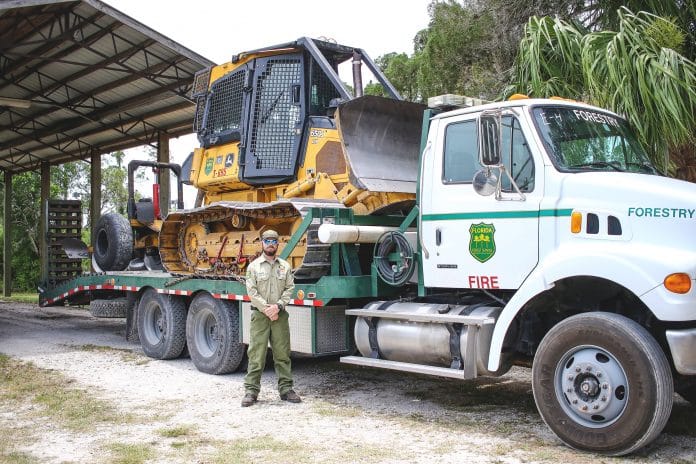 Wildland Firefighter Blake Hunter in front of the John Deer Bulldozer with an attached disc plow he used during the wildfire in Collier County. Photo by Alice Mary Herden