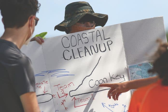 Bryce Ferguson holds the sign as their team leader explains the locations on where their clean up areas are located at Coon Key.