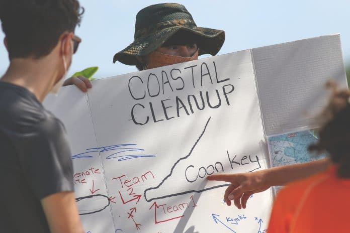 Bryce Ferguson holds the sign as their team leader explains the locations on where their clean up areas are located at Coon Key. 