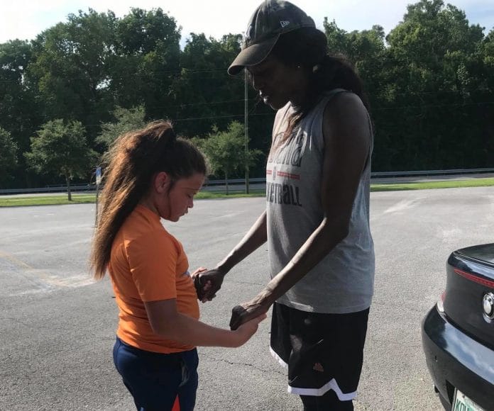 Before practice Bernice Mosby prays on the court with her student athlete.