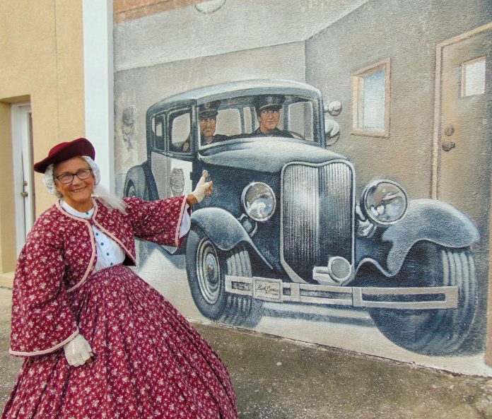 Jan Knowles in front of the Brookville Fire Department/ Police Department mural on East Liberty Street.