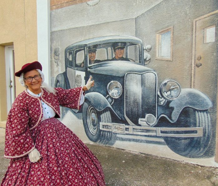 Jan Knowles in front of the Brookville Fire Department/ Police Department mural on East Liberty Street. 