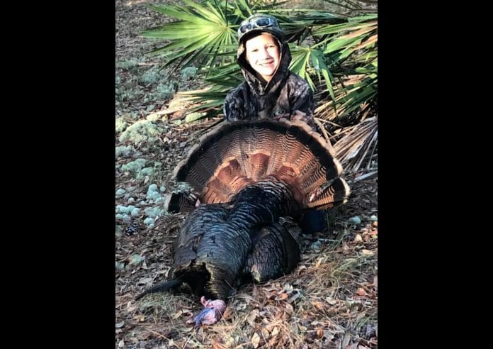 Eight year old Owen Flanders posing proudly with his first gobbler after a hunt with his Uncle Toby