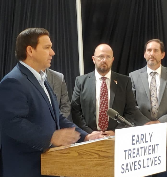 Governor DeSantis addresses the press in Hudson last month and announces the opening of the monoclonal antibody treatment center there.  Background (L-R) Kevin Guthrie, Dr. Kenneth Scheppke. Photo by Sarah Nachin.