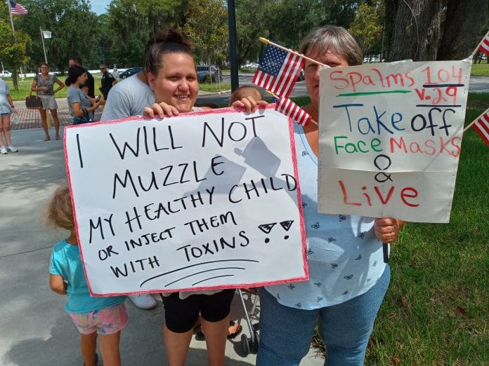 Amber Seymour (left) and Laura Butler hold signs outside of the school board's district office on Aug. 31.