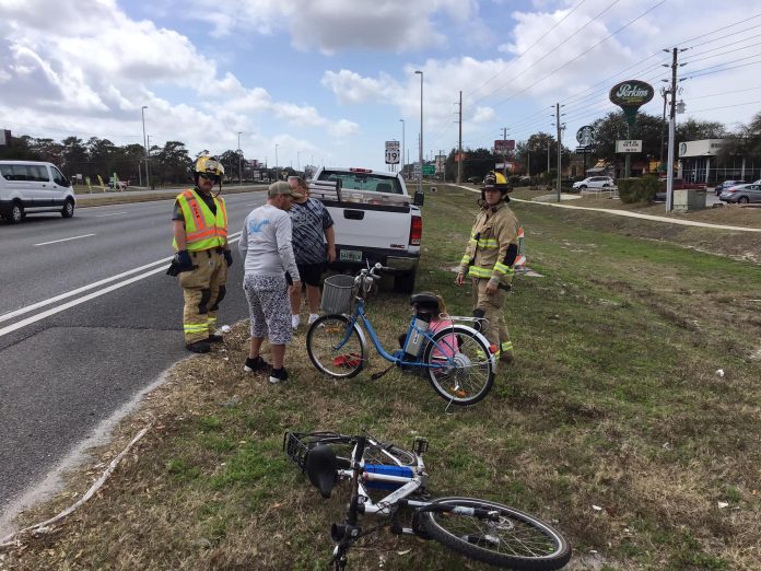 Paramedics and witnesses attend to an unidentified female who was struck by a vehicle crossing Commercial Way