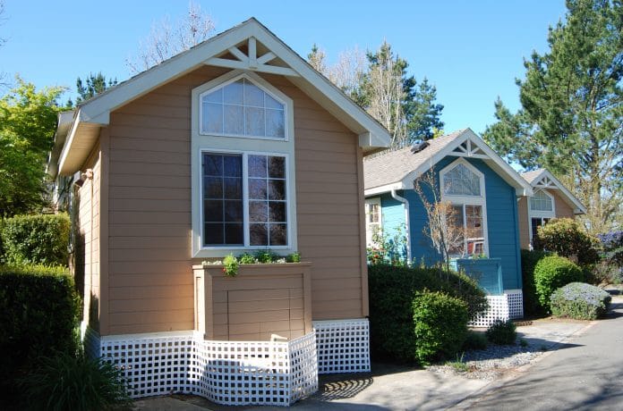 Three very small houses next to each other. Small eco-footprint. Tiny houses photo by Cris Kelly via AdobeStock