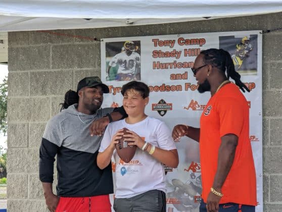 Camp attendee taking picture with two former NFL Players