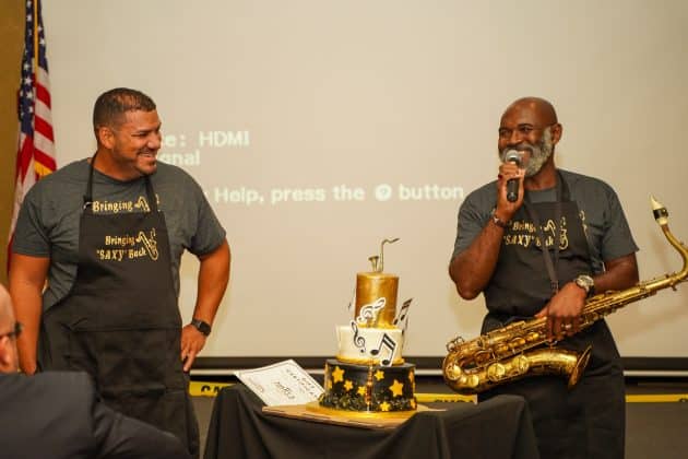 Mike Lastra, left, and Dell Barnes, right, present their ‘saxy’ cake at the 7th Annual Men’s Bake.