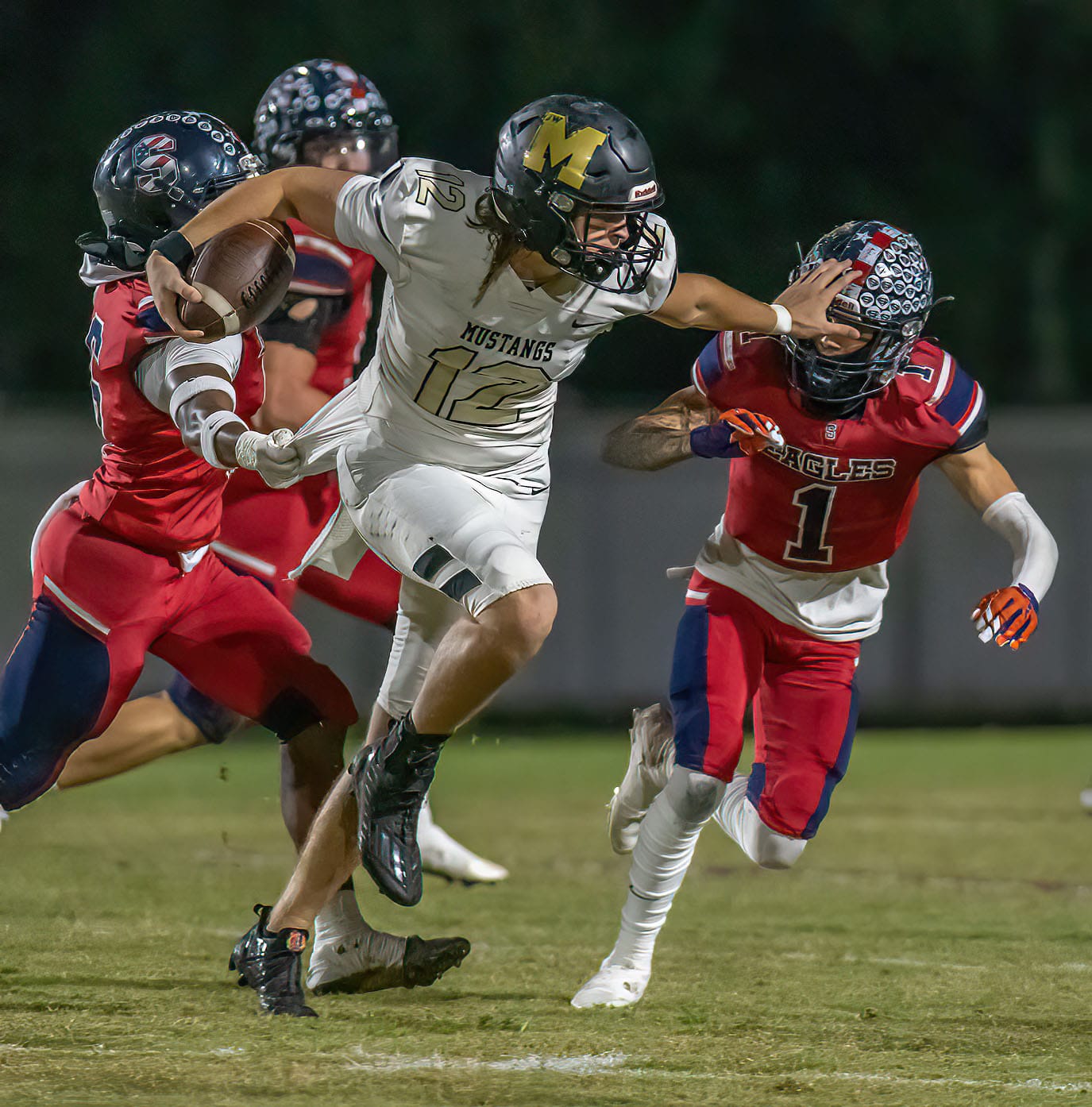 Mitchell QB, 12, Chris Ferrini, proved tough to stop for the Springstead defense, uses a straight arm on, 1, Luca Garguillo who with, 6, Xavier Harris combined for the tackle. Photo by JOE DiCRISTOFALO