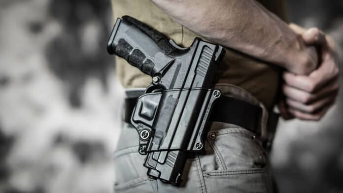 Man openly carrying a pistol on his belt. Open carry and second amendment concept. By Reed/ Adobe Stock