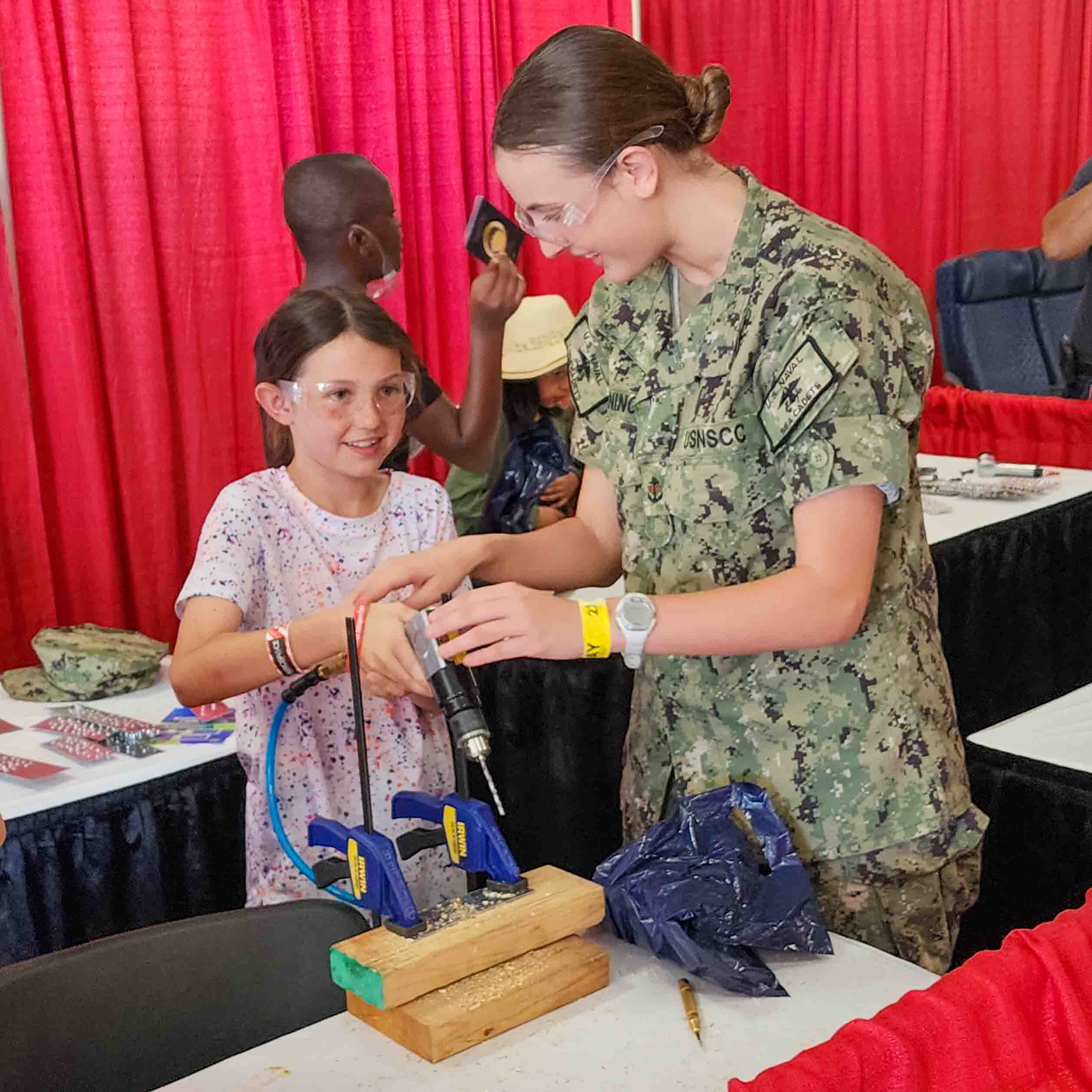 Naval Sea Cadet Breanna Peninger shows Cheyenne Johnson (10) of Warner Robbins, GA. the finer points of using power tools for aircraft construction. Photo credit: Mark Stone