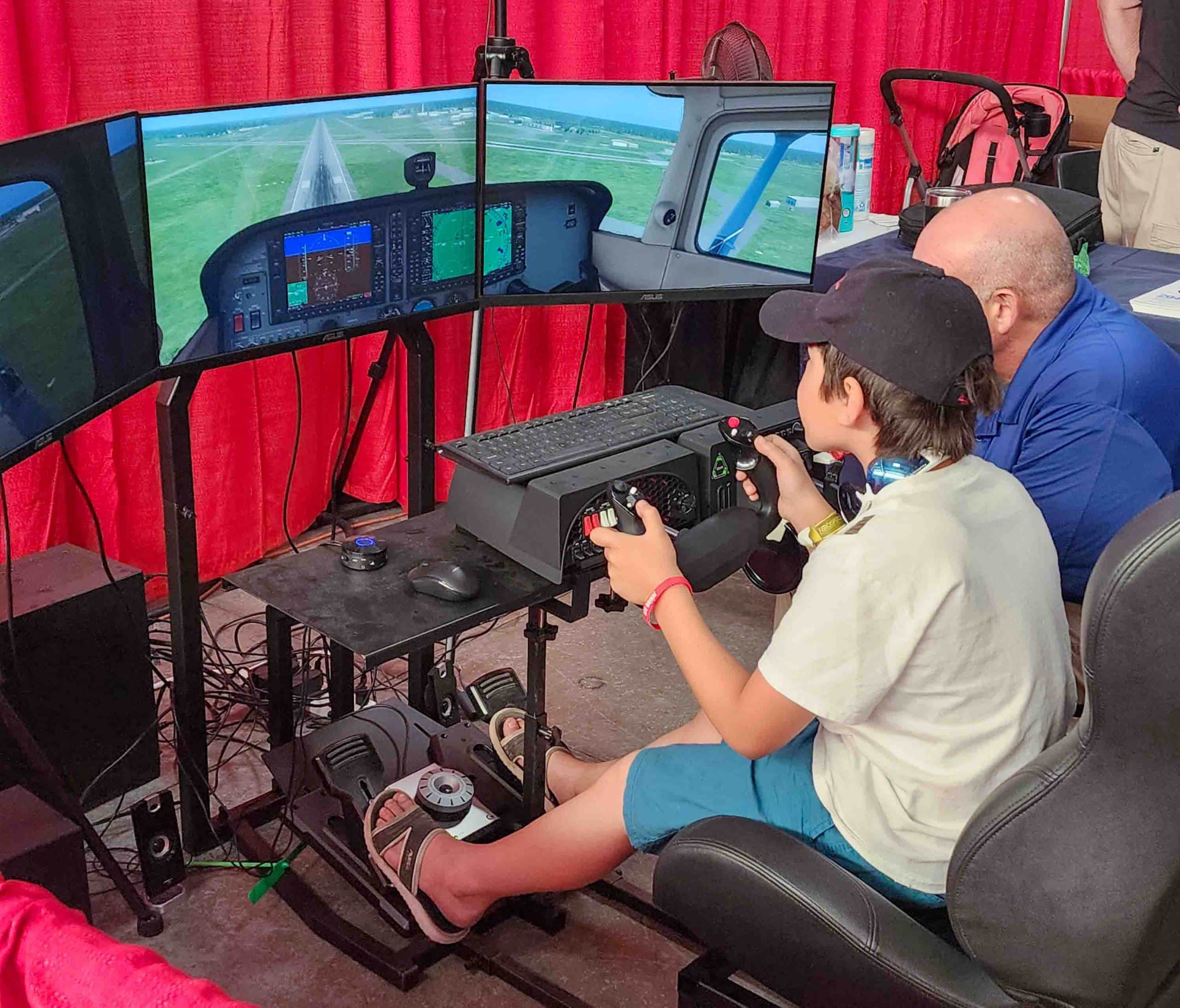 Bryson Ziemer (10) of Crestview, Fla., tries his hand at a flight simulator with guidance from an Embry-Riddle Aeronautical University instructor. Photo credit: Mark Stone