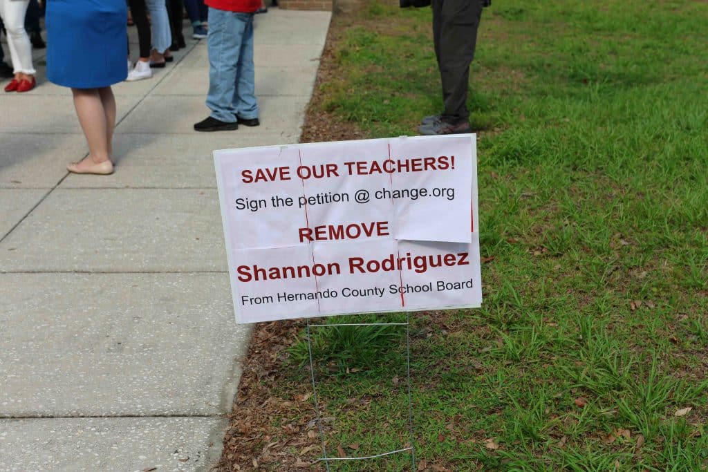 A sign outside the auditorium calls for the removal of board member Shannon Rodriguez. Photo by Mark Stone.