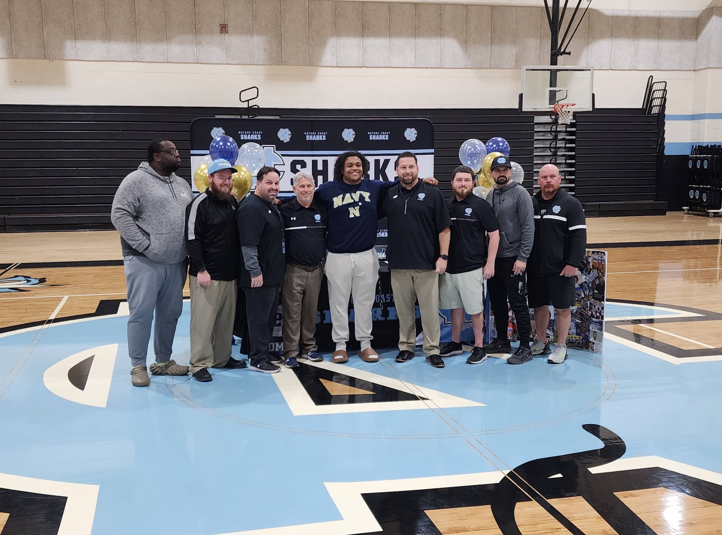 Christian Cromer poses for pictures with Coach Robert Kazmier and the rest of the football staff on signing day. [Credit: A. Szempruch]