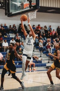 Central, 21, David Villarroel scores a layup between Lakewood defenders, 23, Melvion Wallace and, 0, Elijah Davis during the Bears' quarterfinal victory. [Photo by Cynthia Leota]