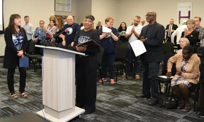 Terri Washington receives a standing ovation at the podium after accepting her award. [Credit: HCSD]