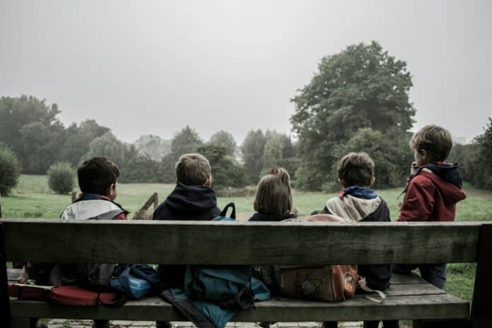 Group of children sitting on a bench.