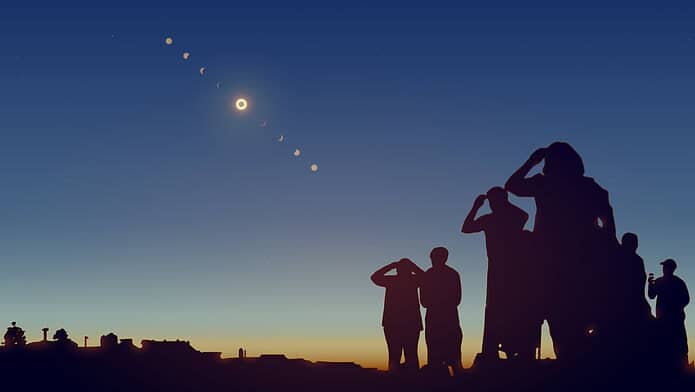 People are watching a solar eclipse in the sky with stars.