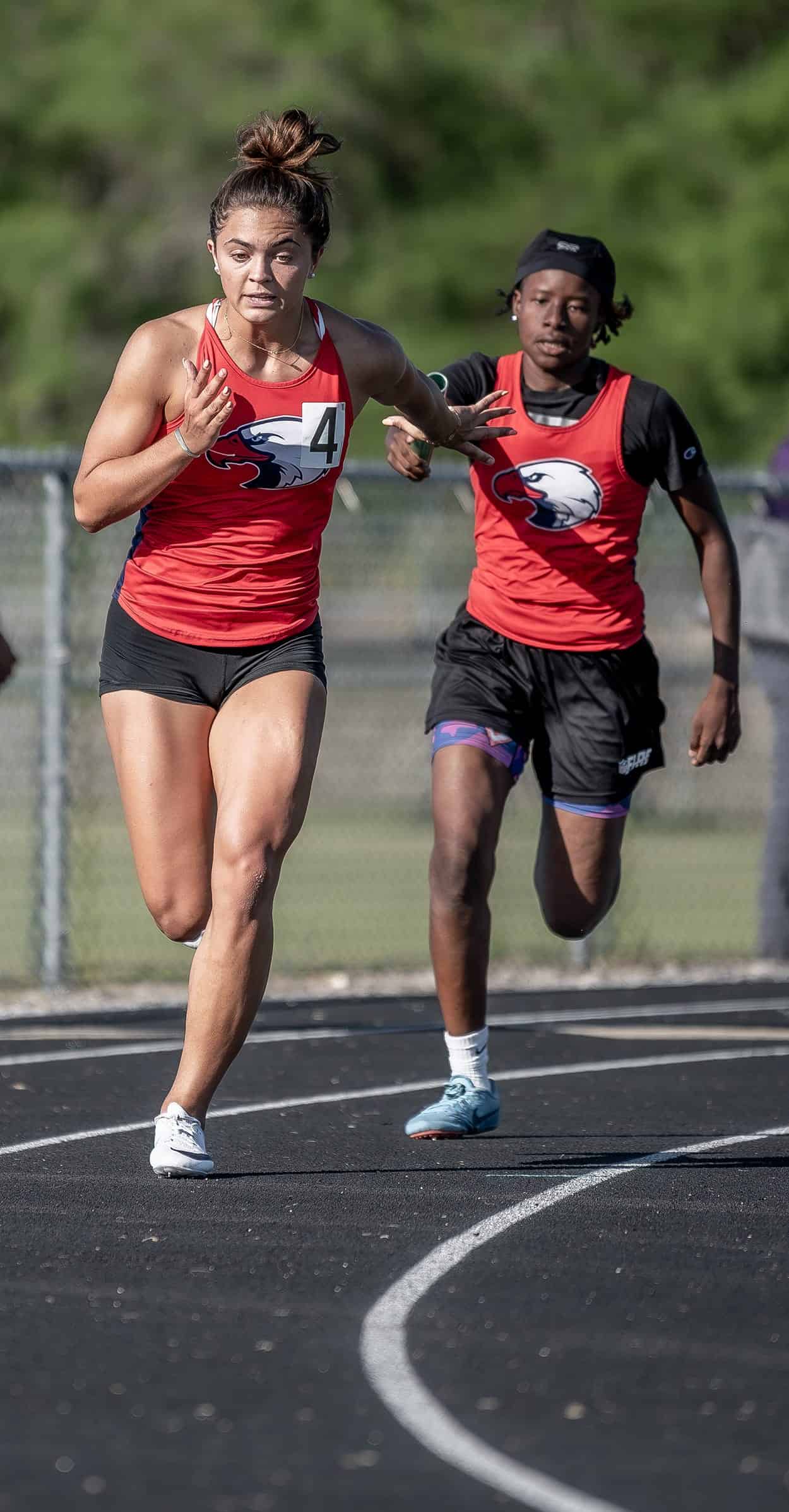 Springstead High’s Ava Kanaar takes the baton from J’Ziyah Munford to anchor the winning 4x100 relay team at the GC8 Track and Field Championships at Weeki Wachee High School. Photo by [Joe DiCristofalo]
