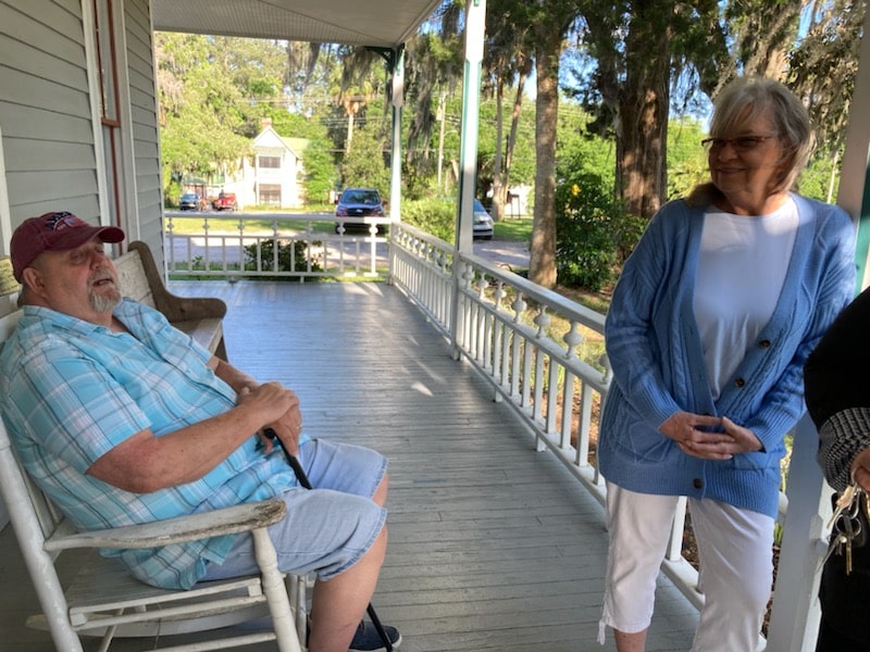 Stan (left) relaxes outside the house while talking to other attendees. [Photo by Mary Sheldon]