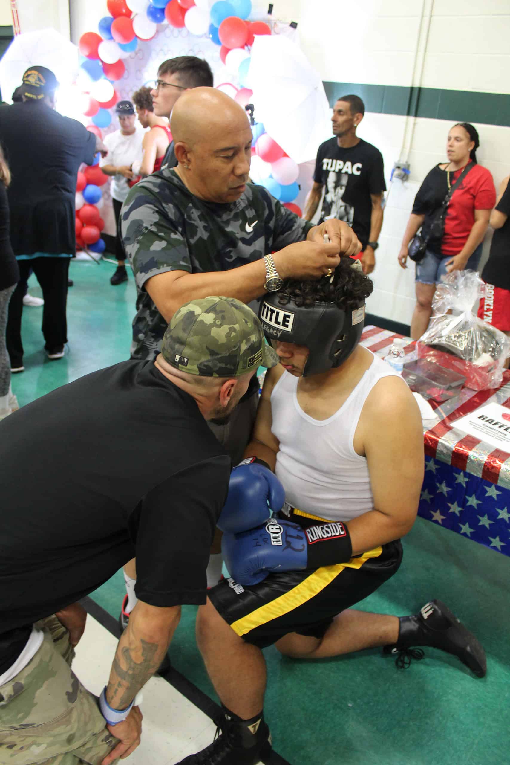 Coach Mendoza (left) and Coach Bruce (middle) of Team Wolfpack Boxing prepare Sebastian Cancel (right) for his bout on Sunday.