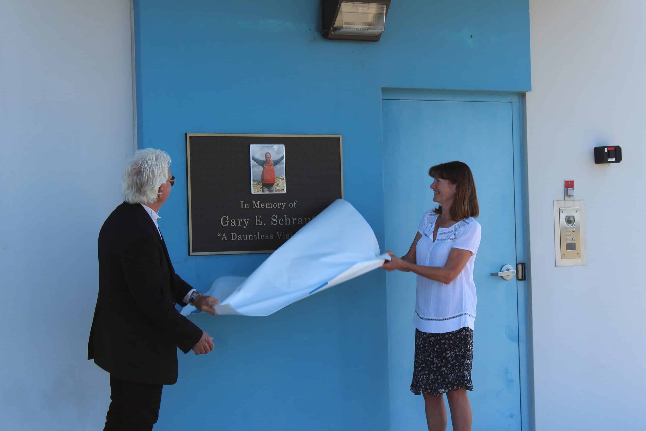 David Russell (left) and Jody Shannon (right) unveil a plaque to Gary Schraut at the air traffic control tower. [Photo by Austyn Szempruch]