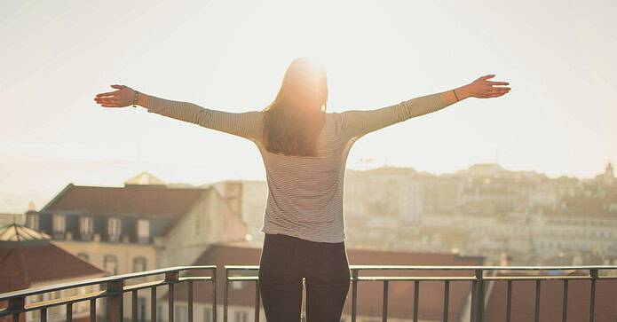 Woman standing with arms stretched in the sunlight
