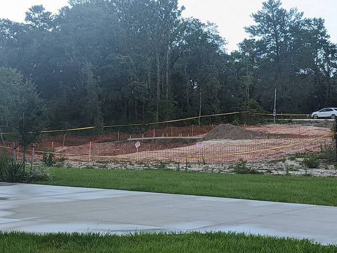 A view of a sinkhole on Mississippi Kite Ave property in Royal Highlands across the driveway of the adjacent home. [Photo by Julie Maglio]